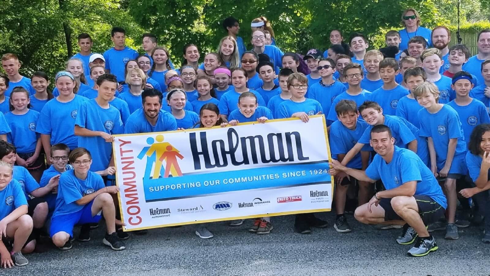 Holman team holding a Holman community banner